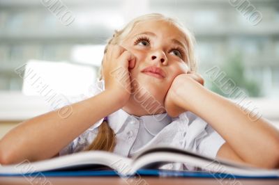 Portrait of a young girl in school at the desk.