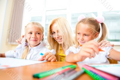 Young pretty teacher helping to her students to make exercise in