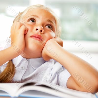 Portrait of a young girl in school at the desk.