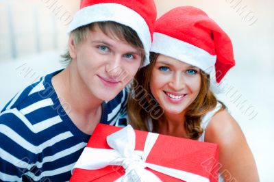 Portrait of young pretty couple standing indoors wearing Santa C