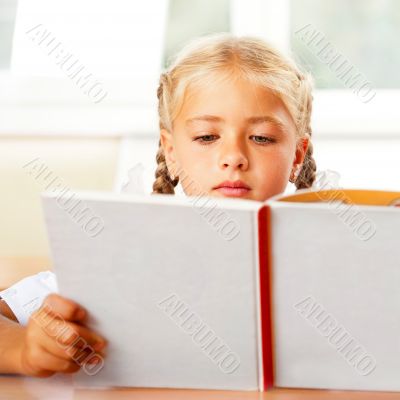 Image of smart child reading interesting book in classroom. Hori