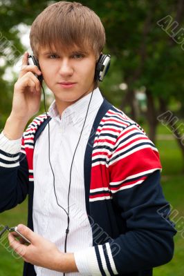 Student listening language course in headphones outside school