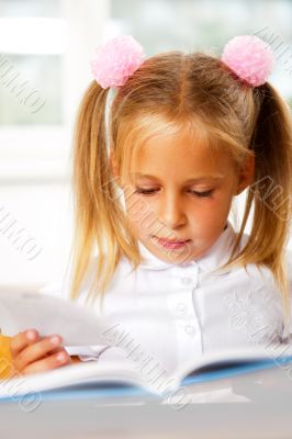 Image of smart child reading interesting book in classroom