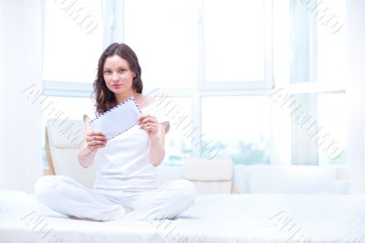 American or european young pretty woman sitting on bed in bright