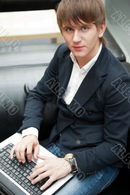 Portrait of handsome young man working with laptop at cafe at bu