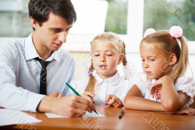 Teacher helping elementary school pupils with their tasks
