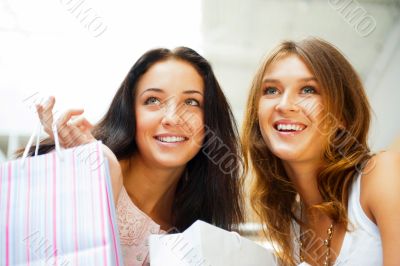 Two excited shopping woman together inside shopping mall. Horizo