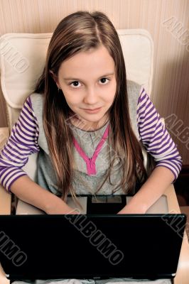 Young girl doing she`s work on laptop sitting on armchair