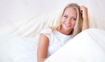 Young blond woman enjoying a sunny morning in bed
