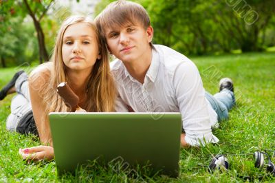 College students using laptop on campus lawn