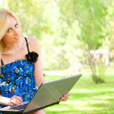 Portrait of a pretty student woman leaning on the tree trunk on 