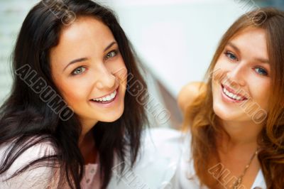 Two women whispering and smiling while shopping inside mall