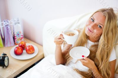 Young woman at home sipping tea or coffee from a cup