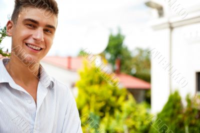 Satisfied smiling businessman standing in the green outdoors.