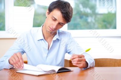 Businessman sitting indoors and writing plan in his diary