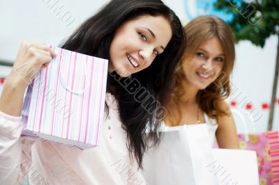 Two excited shopping woman resting on bench at shopping mall loo