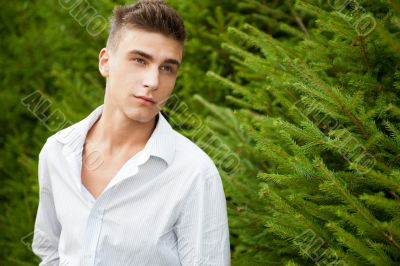 Satisfied smiling businessman standing in the green outdoors.