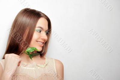 Portrait of young pretty woman holding green leaves