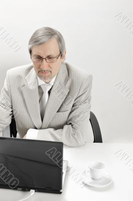 Portrait of an older businessman with a computer and a cup.