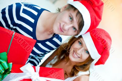 Young happy couple in Christmas hats standing together and holdi