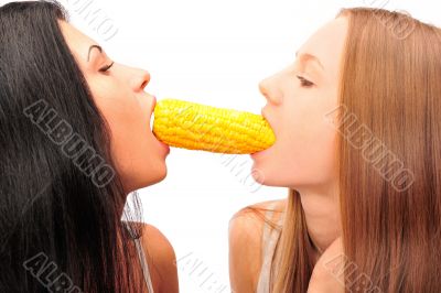 Two women eating corn at the same time from different sides