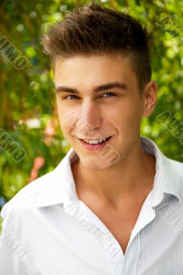 Satisfied smiling businessman standing in the green outdoors.