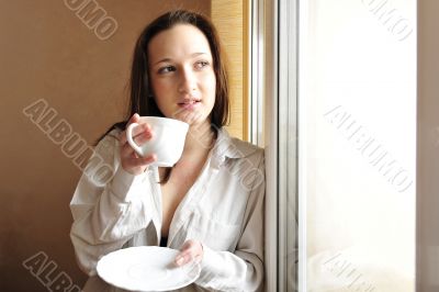 Portrait of cosy young girl standing near a window at home