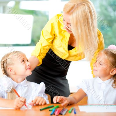 Young pretty teacher helping to her students to make exercise in