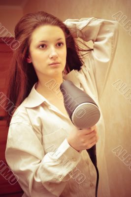 Beautiful woman drying her hair with hairdryer