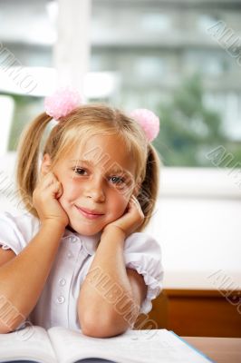 Image of smart child reading interesting book in classroom
