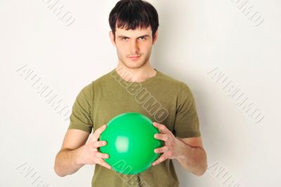 Portrait of handsome man holding green ball in his arms. Standin