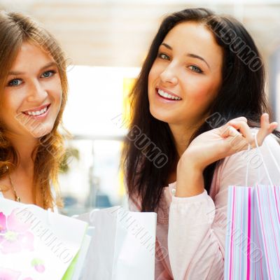 Two excited shopping woman together inside shopping mall. Horizo