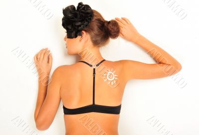 Sunscreen lotion over tan woman skin made as sun shape