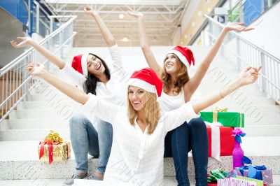 Group of three beautiful girls sitting on stairs at shopping mal