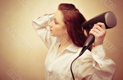 Beautiful woman drying her hair with hairdryer