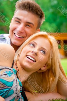 Portrait of beautiful young couple sitting on ground in park rel
