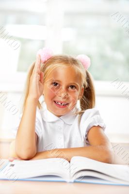 Portrait of a young girl in school at the desk.