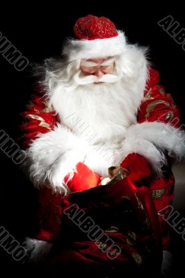 Santa sitting at the Christmas room and looking into the sack