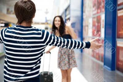 Young man meeting his girlfriend with opened arms at airport arr