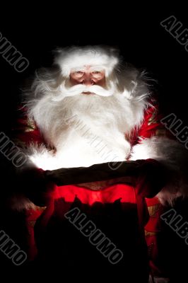 Santa sitting at the Christmas room and looking into the sack
