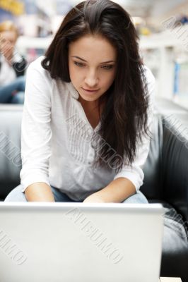 Portrait of a beautiful young woman working on laptop while sitt