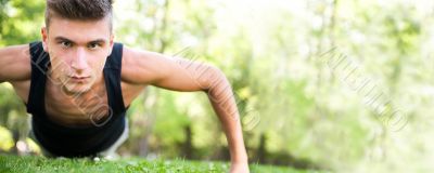 Full length of young man full of attitude doing pushups on grass