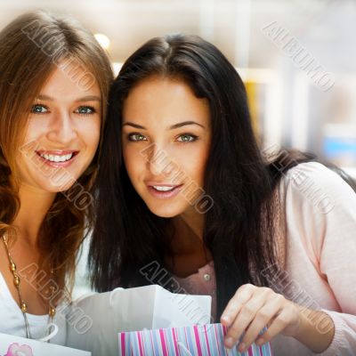 Two excited shopping woman resting on bench at shopping mall loo Two excited shopping woman resting on bench at shopping mall loo