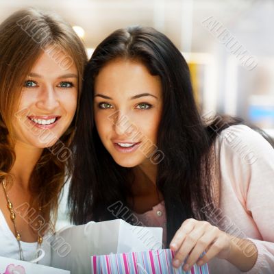 Two excited shopping woman resting on bench at shopping mall loo