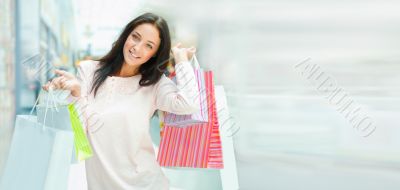 Photo of young joyful woman with shopping bags on the background