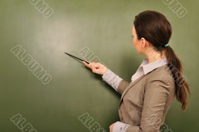 Portrait of young woman teacher standing near blackboard and exp