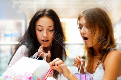 Two excited shopping woman together inside shopping mall. Horizo