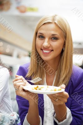 Closeup portrait of an attractive young woman eating fruit salad