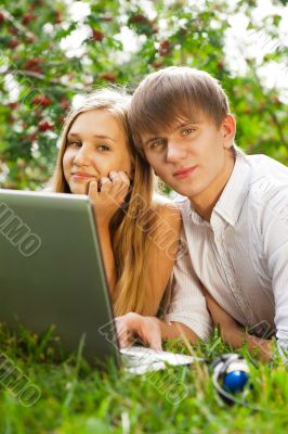 College students using laptop on campus lawn