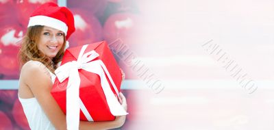 Young happy girl in Christmas hat. Standing indoors and holding 